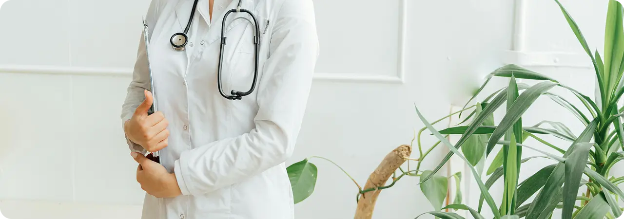 Lekarka w białym fartuchu trzyma teczkę z dokumentacją medyczną